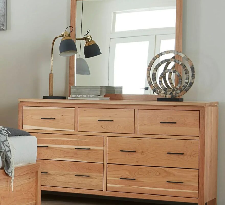 Light wood seven-drawer dresser with mirror and decor.